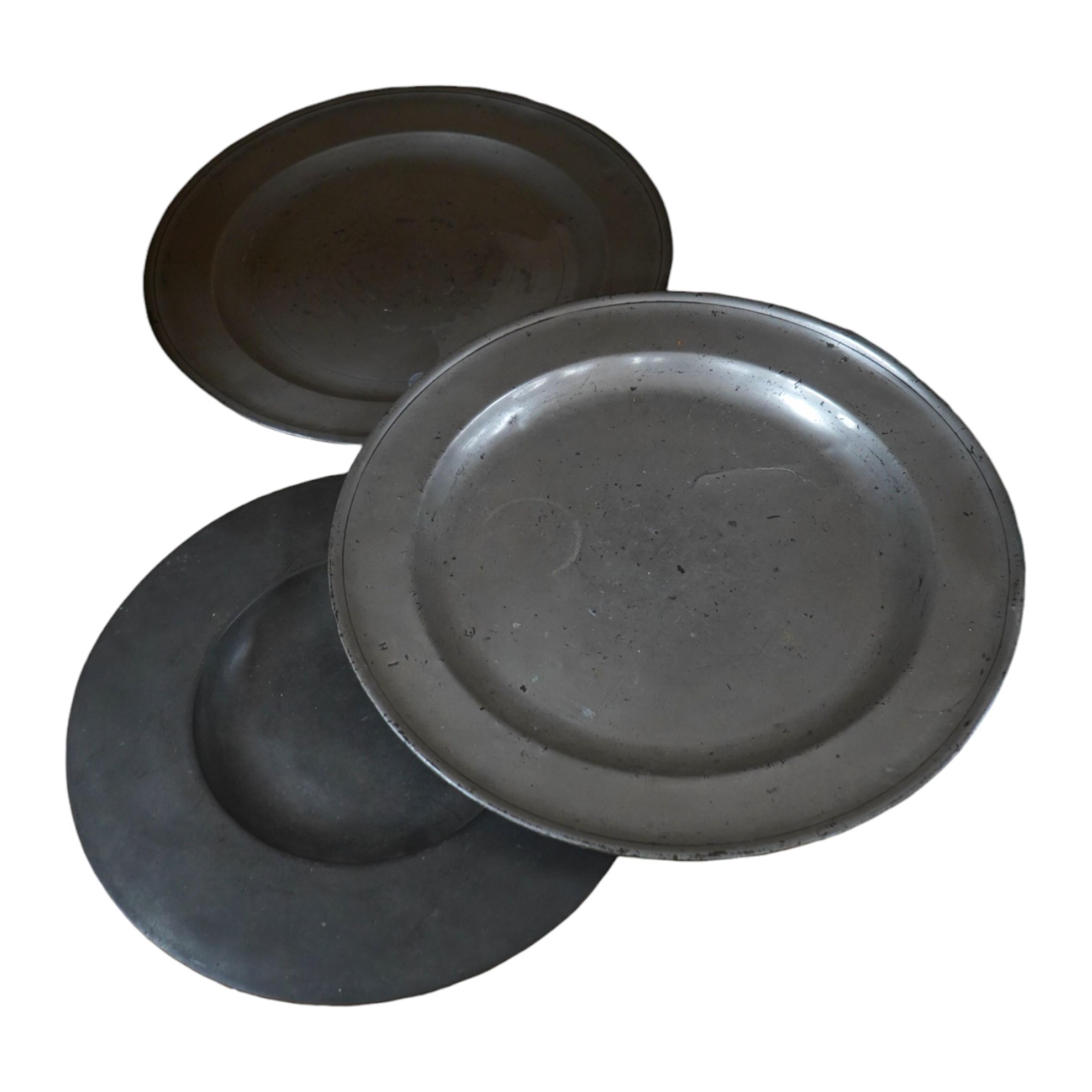 Three pewter chargers, a London touch mark to one, another with rubbed touch marks and ‘WRM’, and another with remains of a touch mark, largest 42.5cm diameter. Condition - fair, worn with damage to one